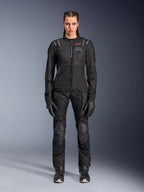 Casaco Alpinestars Stella ST-2 Air, preto, vista de estúdio de corpo inteiro de uma motociclista a usar calças e luvas de motociclismo pretas a condizer, com painéis de malha de elevado fluxo de ar, detalhes de logótipo a vermelho e um design de touring moderno