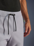 Alpinestars Aeroshell Pants, Cinzento Médio com detalhes em Amarelo Flúor, vista aproximada da cintura elástica com fecho de cordão preto e ilhoses metálicos da marca, pormenor do tecido softshell elástico
