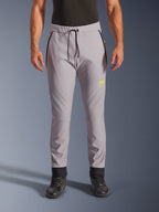 Alpinestars Aeroshell Pants, cinzento médio e amarelo fluo, calças de motociclismo softshell crossover, com cintura de cordão preto e punhos ajustados nos tornozelos, logótipo amarelo na coxa esquerda, joelhos pré-curvados, silhueta desportiva estilo jogger