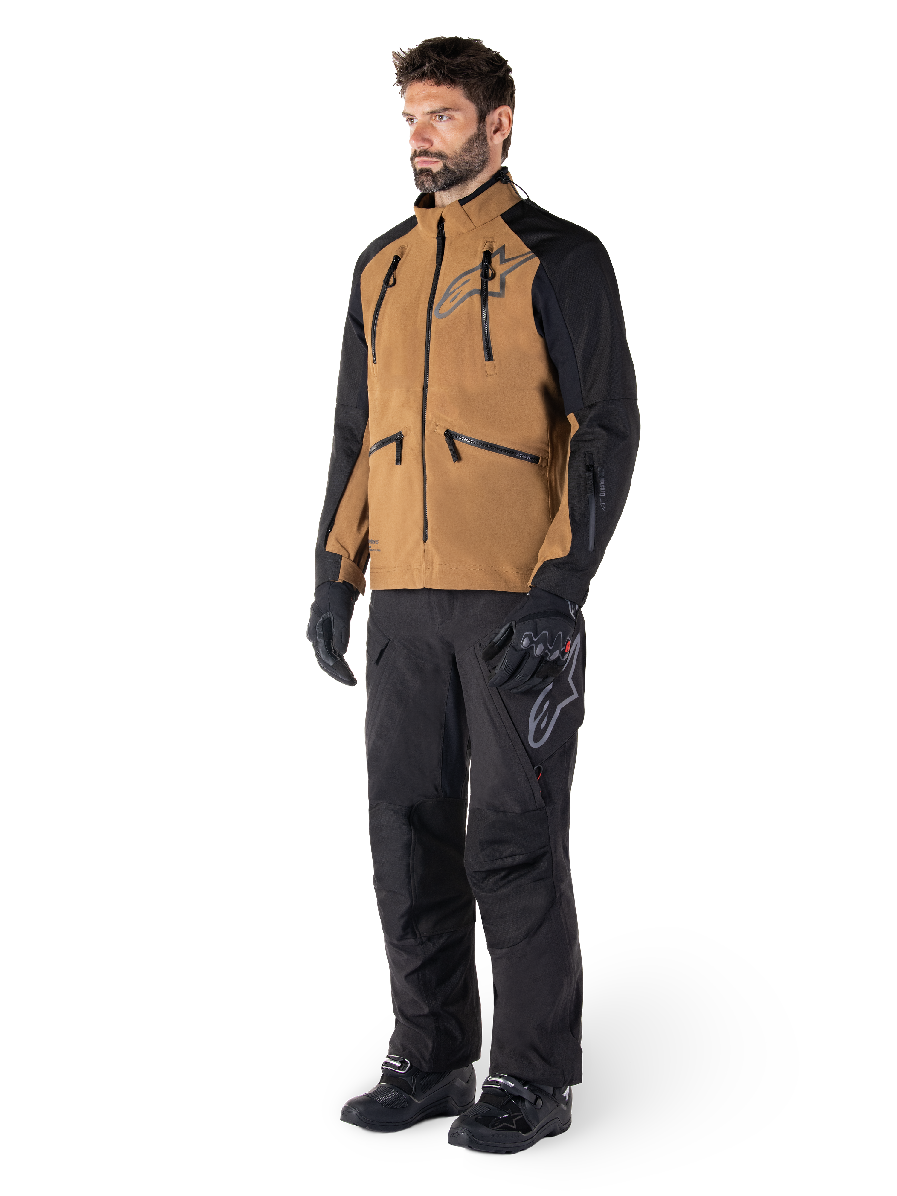 Calças Alpinestars Hyde XT Drystar®, calças de motociclismo de aventura, pretas, usadas com um casaco técnico castanho e preto, luvas e botas pretas, com um design por cima da bota para condução off-road e dual-sport