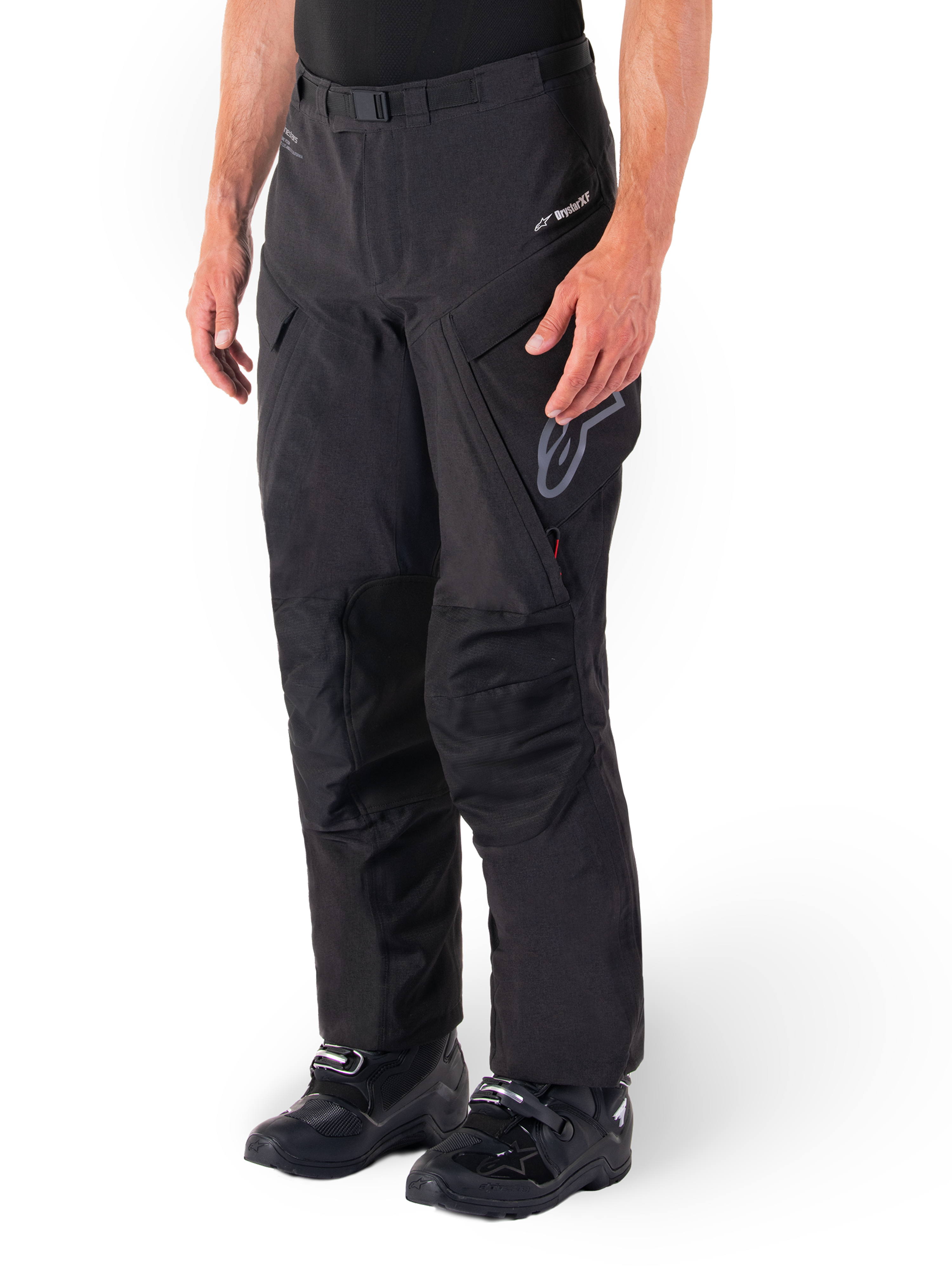 Calças Alpinestars Hyde XT Drystar®, calças de motociclismo Adventure Touring, pretas, usadas com botas pretas, apresentando o logótipo da membrana laminada Drystar®XF, painéis reforçados nos joelhos e bolsos de carga com fecho de correr.