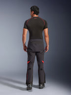Calças Alpinestars Halo Pro Drystar® XF Laminated, calças de motociclismo de aventura, Preto Dark Shadow com detalhes em vermelho, vista traseira, usadas com uma camisola interior de manga curta preta e botas de aventura pretas, construção laminada de 3 camadas e ajuste ergonómico.