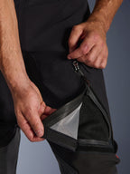 Alpinestars Halo Pro Drystar® XF Laminated Pants, pretas, grande plano de uma pessoa a abrir a abertura de ventilação na coxa com um fecho impermeável, revelando um forro de malha preta para ventilação direta, detalhe funcional de calças de motociclismo de aventura.