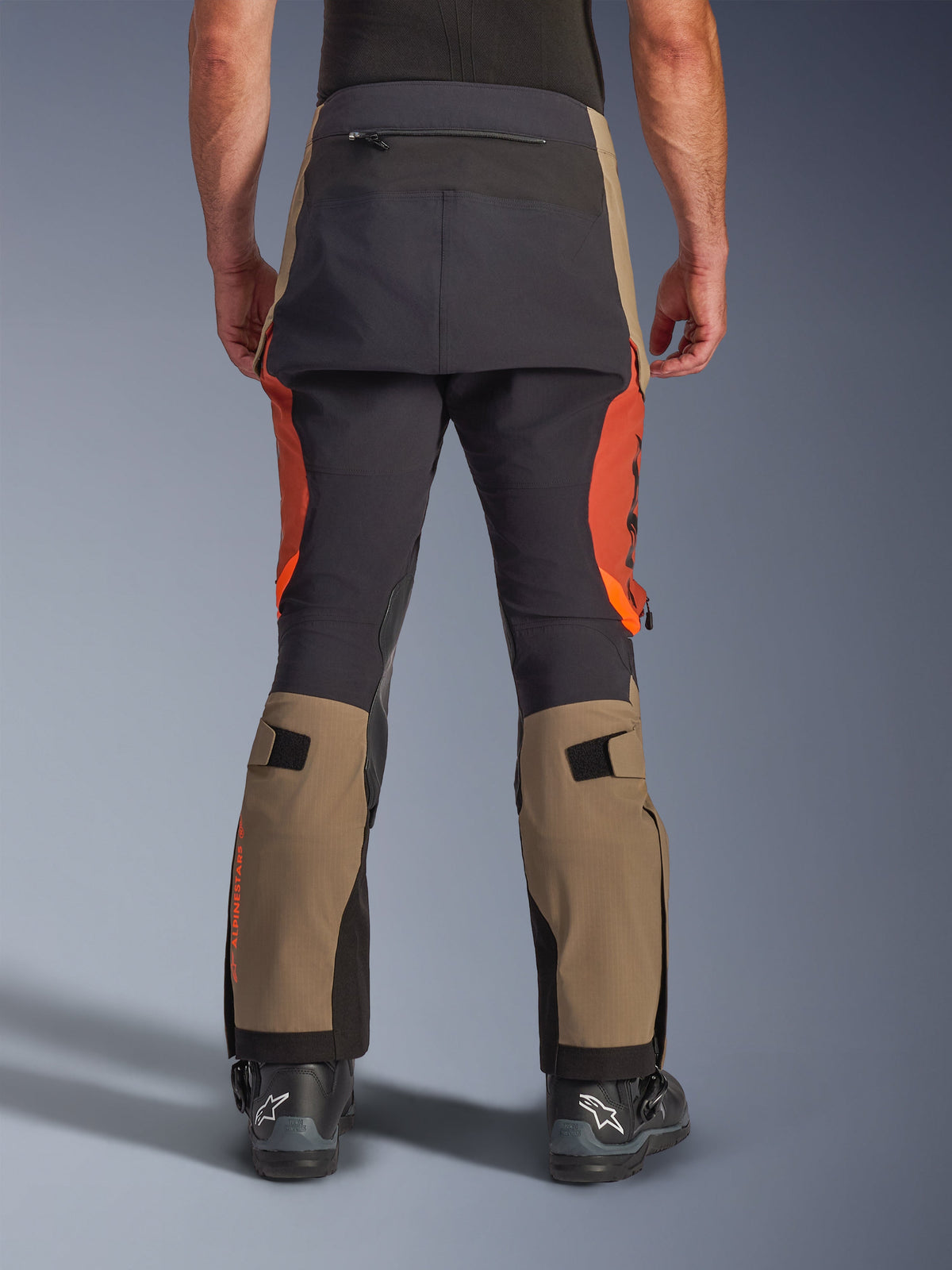 Calças Alpinestars Halo Pro Drystar® XF Laminated em Walnut Rust Black, vista traseira, calças de motociclismo de aventura com painéis em castanho nogueira e laranja ferrugem, reforço de assento preto, inclui bolso traseiro com fecho e tiras de ajuste de volume na panturrilha