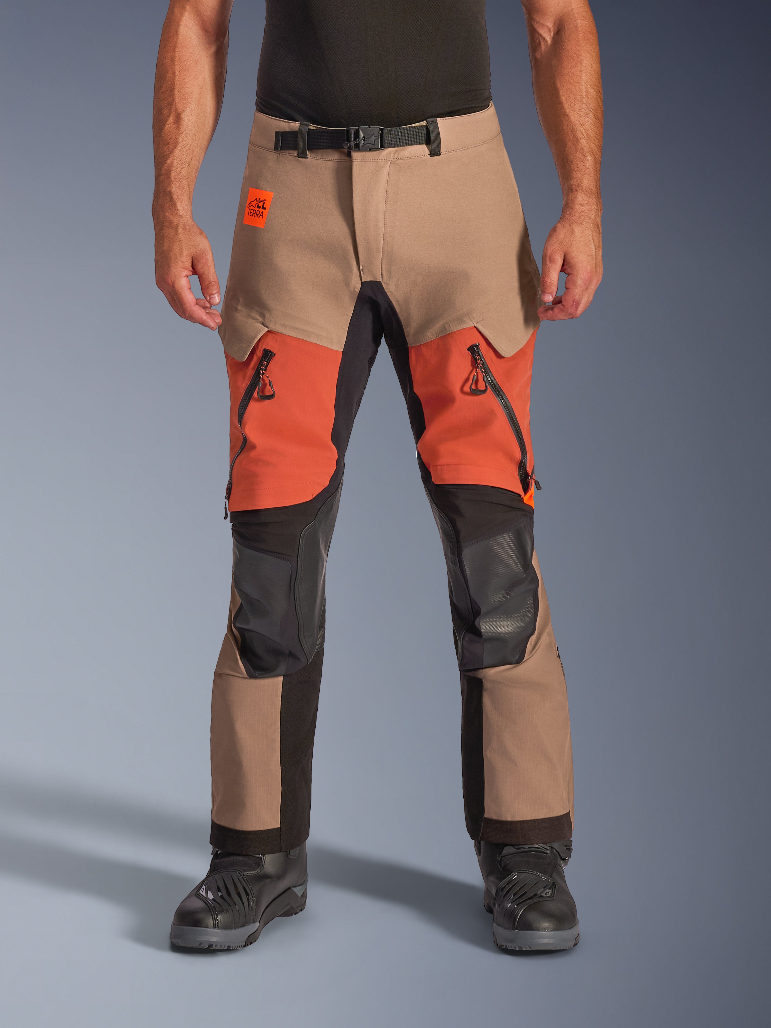 Alpinestars Halo Pro Drystar XF Laminated Pants, calças de motociclismo para turismo de aventura, nogueira, ferrugem e preto, com construção laminada impermeável, vista frontal com aberturas de ventilação cor de laranja nas coxas, fechos pretos YKK AQUASEAL e cinto ajustável na cintura.
