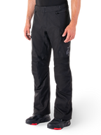 Alpinestars ST-1 Waterproof Pants, Black Motorcycle Touring Pants, worn with black and red riding boots, featuring zippered front pockets and a subtle star logo on the thigh, ergonomic design for adventure and road riding.