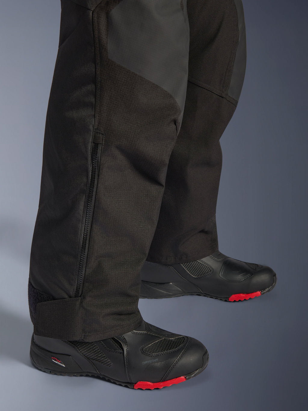 Alpinestars Andes V4 Drystar® Pants - Short, Black, close-up of lower leg detail showing textile construction, vertical zipper for ventilation, and adjustable ankle cuffs, worn with black motorcycle boots