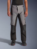 Alpinestars Andes V4 Drystar® Pants, calças de motociclismo para turismo e aventura, cinzentas e pretas, vista frontal vestidas por um modelo com botas de motociclista pretas, com reforços nos joelhos e bolsos cargo nas coxas, construção têxtil impermeável e respirável para condução em todas as condições meteorológicas