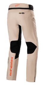 Alpinestars AMT-10R Drystar® XF Pants, calças de aventura e turismo, castanho claro, vista traseira com grandes painéis de malha preta na parte de trás dos joelhos, logótipos Alpinestars cor-de-laranja no cós e na parte inferior da perna, e identificação dos materiais Kevlar e MATRYX
