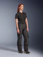Calças Alpinestars Stella Andes V4 Drystar®, calças de motociclismo para mulher, pretas, usadas com uma t-shirt preta de manga curta com logótipo vermelho e calçado técnico, design de aventura touring com painéis reforçados e fechos de ventilação, vista de corpo inteiro em três quartos