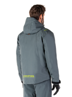 Alpinestars Morush Waterproof Parka in Urban Gray, rear view, featuring yellow MO.ST.EQ. branding on the lower back and shoulder, minimalist hooded design, worn with matching gray riding pants and black gloves, urban motorcycle streetwear.
