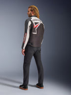 Casaco Alpinestars Axton, casaco de motociclismo, preto, branco sujo e vermelho vivo, vista traseira usada por modelo masculino, com grande logótipo de estrela e marca Alpinestars nas costas, design de inspiração vintage com painéis de acordeão, combinado com calças pretas e sapatilhas