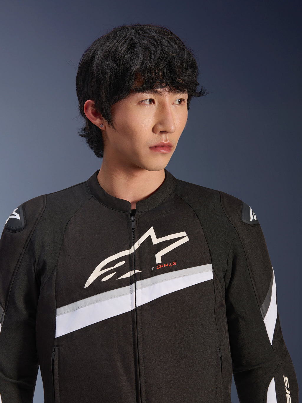 Alpinestars T-GP Plus R V4 Jacket, Black and White, textile motorcycle jacket worn by a male model, featuring a large white star logo on the chest, white diagonal stripes, and DFS Lite shoulder protectors, sport-inspired street riding gear.