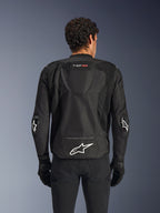 Casaco Alpinestars T-GP Air, Preto, vista traseira de casaco de motociclismo têxtil, com uma corcunda aerodinâmica, grandes painéis de ventilação em malha e logótipo Alpinestars branco na parte inferior das costas, combinado com luvas e calças de motociclismo pretas