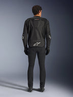 Casaco Alpinestars T-GP Air, Preto, vista traseira de um homem a usar o casaco de motociclista têxtil, com painéis de ventilação em malha, uma corcunda aerodinâmica e logótipos Alpinestars brancos na zona lombar e nos cotovelos, usado com calças de condução e luvas pretas