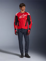 Alpinestars T-GP Air Jacket, Bright Red Red Fluo Black, male model wearing full motorcycle outfit with dark blue jeans and matching gloves, sport textile jacket featuring perforated mesh panels and white Astars logo, studio shot.