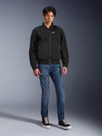 Casaco Alpinestars Flight Air, Preto, casaco de motociclista estilo bomber de inspiração urbana com painéis de malha 3D e logótipo branco no peito, usado por um modelo com calças de ganga azuis e sapatilhas pretas, vestuário de condução contemporâneo