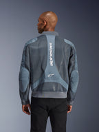 Alpinestars Flight Air Jacket em Storm Gray, vista traseira num modelo, casaco de motociclismo urbano com painéis de malha 3D alargados, marca Alpinestars vertical nas costas, gola e bainha caneladas de estilo bomber