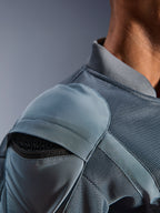 Pormenor do casaco Alpinestars Flight Air Jacket em Storm Gray, realçando o bolso externo para o protetor de ombro com armadura em favo de mel visível, painéis de ventilação em malha 3D e gola canelada para condução urbana técnica de motociclo