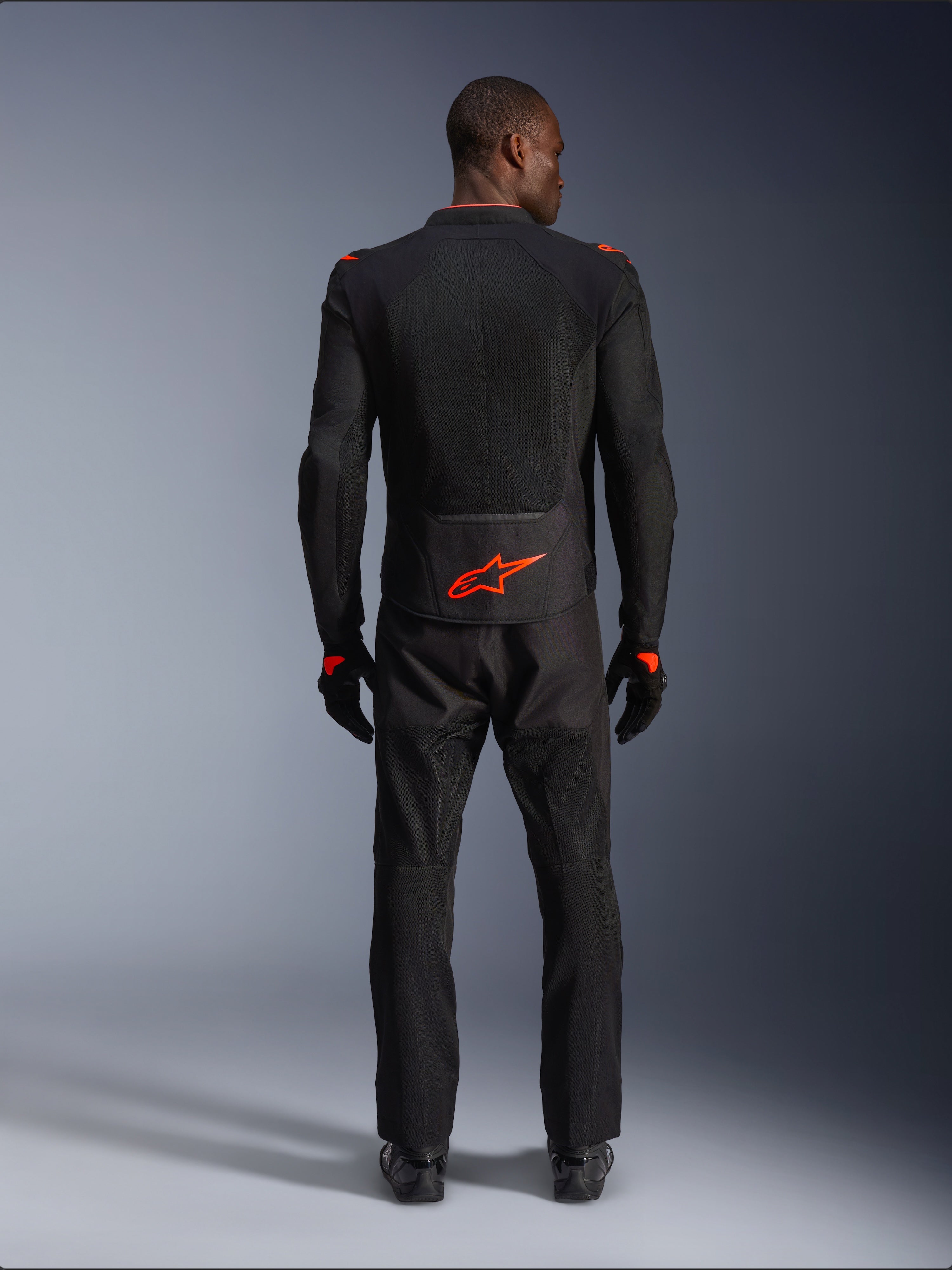 Alpinestars Viper Air V4 Jacket, Black and Red Fluo, rear view on model, worn with matching black riding pants and gloves, featuring a bright fluorescent red logo on the lower back, mesh construction for airflow, athletic fit for motorcycle road riding
