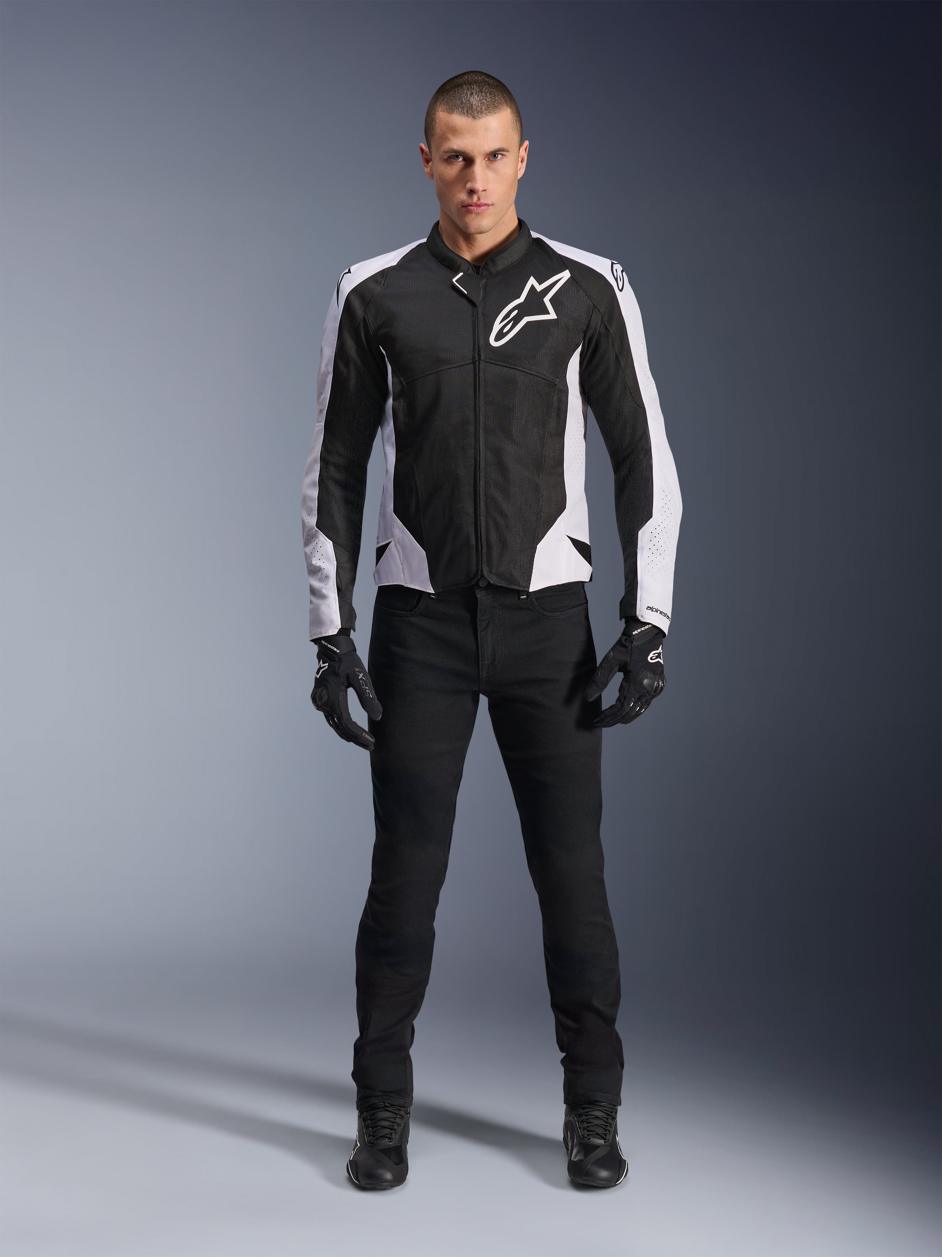 Alpinestars Viper Air V4 Jacket, Black and White motorcycle jacket with large white logo on chest, worn by a male model with black pants and gloves, featuring mesh panels for ventilation, sporty road riding apparel