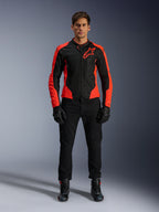 Modelo masculino a usar o Casaco Alpinestars Viper Air V4 em Vermelho Fluo e Preto, combinado com calças de motociclismo, luvas e botas pretas, apresentando painéis de malha respirável para ventilação e um logótipo de estrela proeminente no peito, vestuário desportivo para motociclismo de estrada