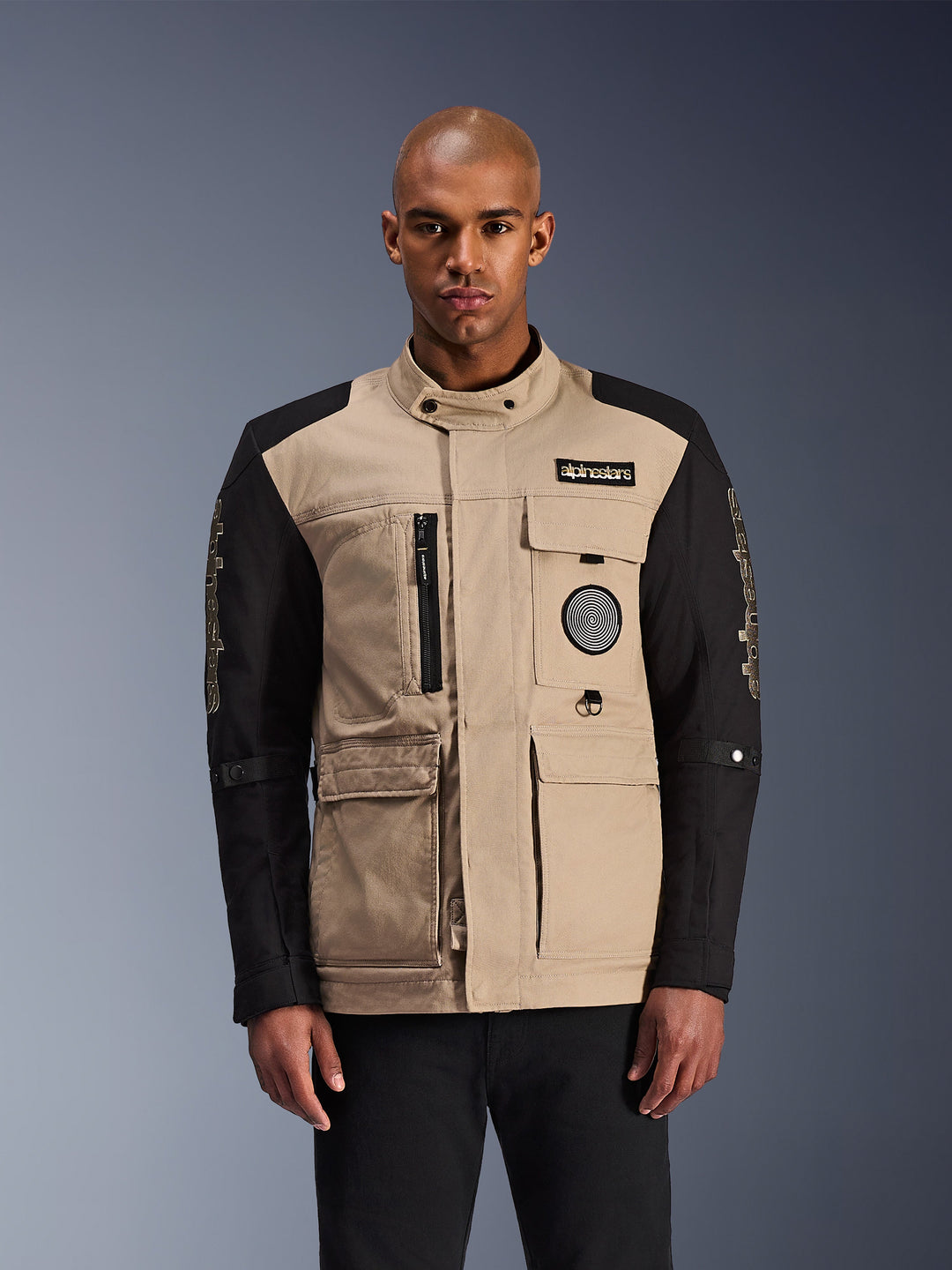 Alpinestars Dice Jacket, casaco de moto urbano unissexo, bege e preto, com múltiplos bolsos, fechos de correr e patches decorativos no peito, colarinho alto com botão
