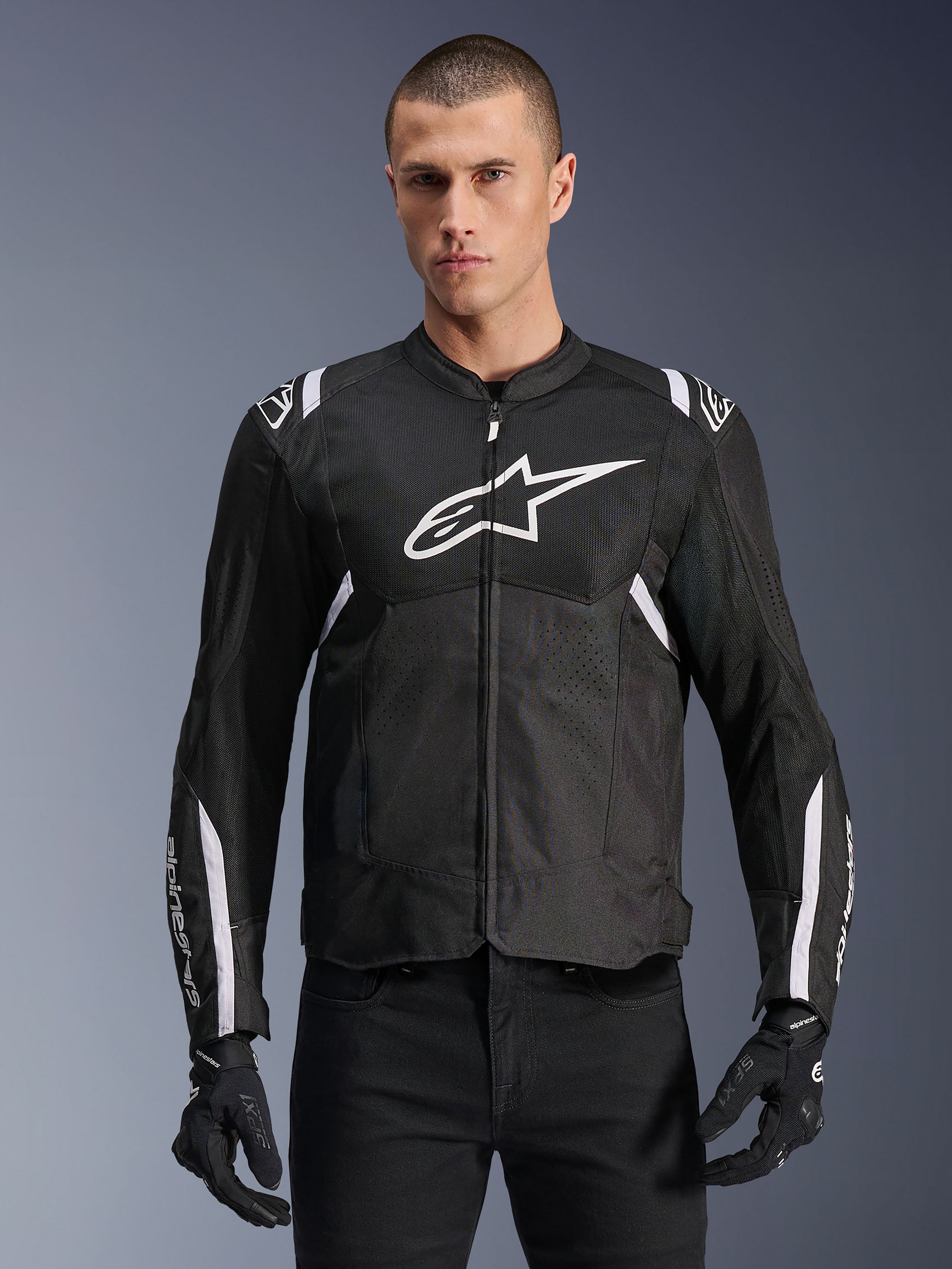 Alpinestars T-SPS Air V2 Jacket, casaco de motociclismo em têxtil, preto com detalhes em branco, logótipo grande branco no peito, design em malha perfurada para ventilação, usado com calças e luvas pretas