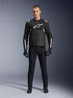 Casaco Alpinestars T-Sps Air V2, casaco de motociclismo em tecido, preto e branco, com um grande logótipo branco no peito e painéis em malha, usado por um modelo com equipamento preto para condução desportiva urbana