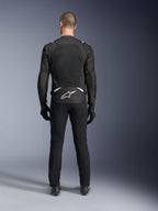 Casaco Alpinestars T-Sps Air V2, vista traseira, casaco de motociclismo em têxtil preto e branco, com um grande painel de malha nas costas para máximo fluxo de ar e logótipo Astars branco na parte inferior das costas, usado com calças e luvas de condução pretas