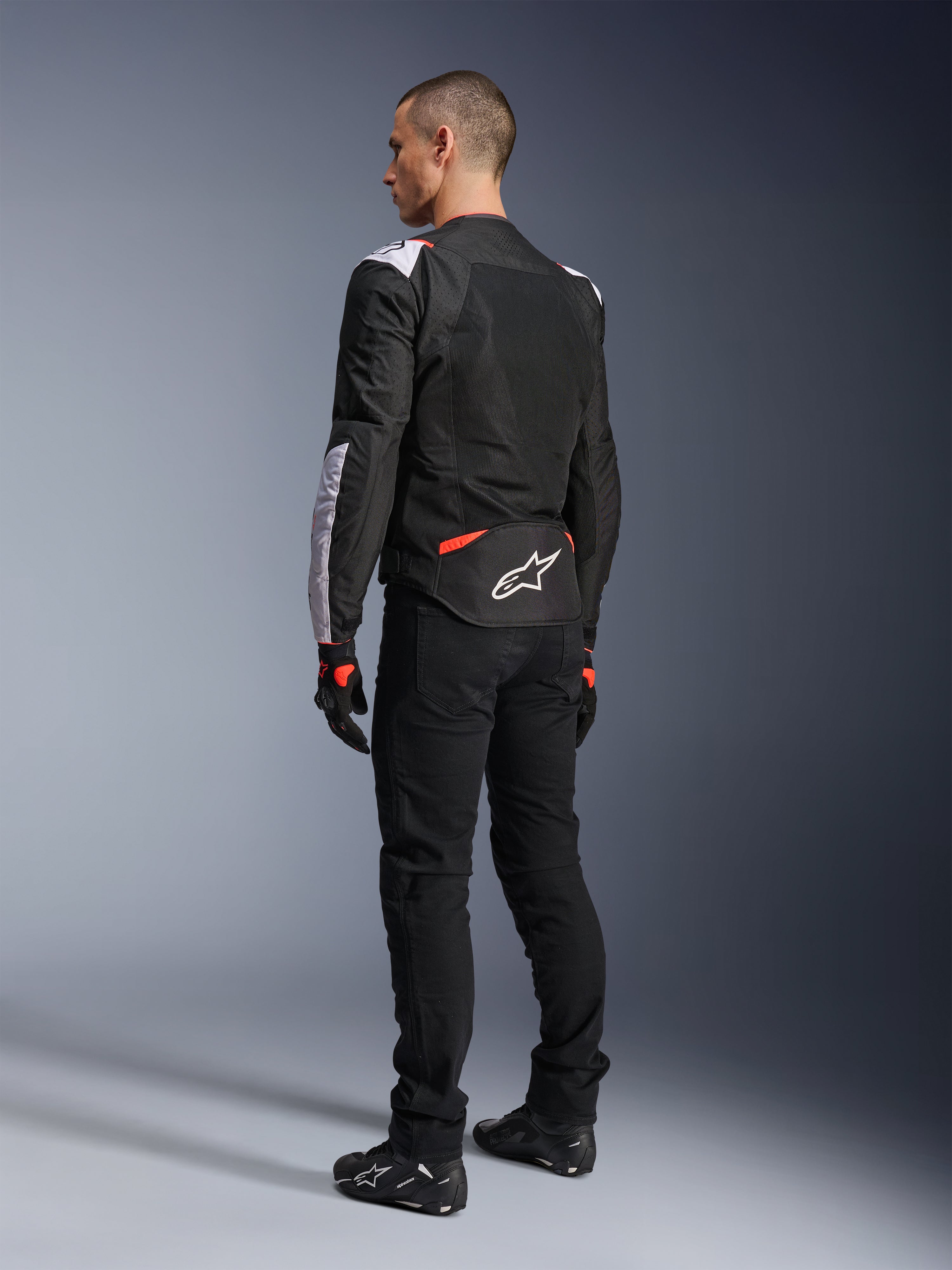Alpinestars T-Sps Air V2 Jacket, Textile Motorcycle Jacket, Black White and Red Fluo, rear view on model, mesh paneling for ventilation, white Astars logo on lower back, styled with black riding pants and gloves