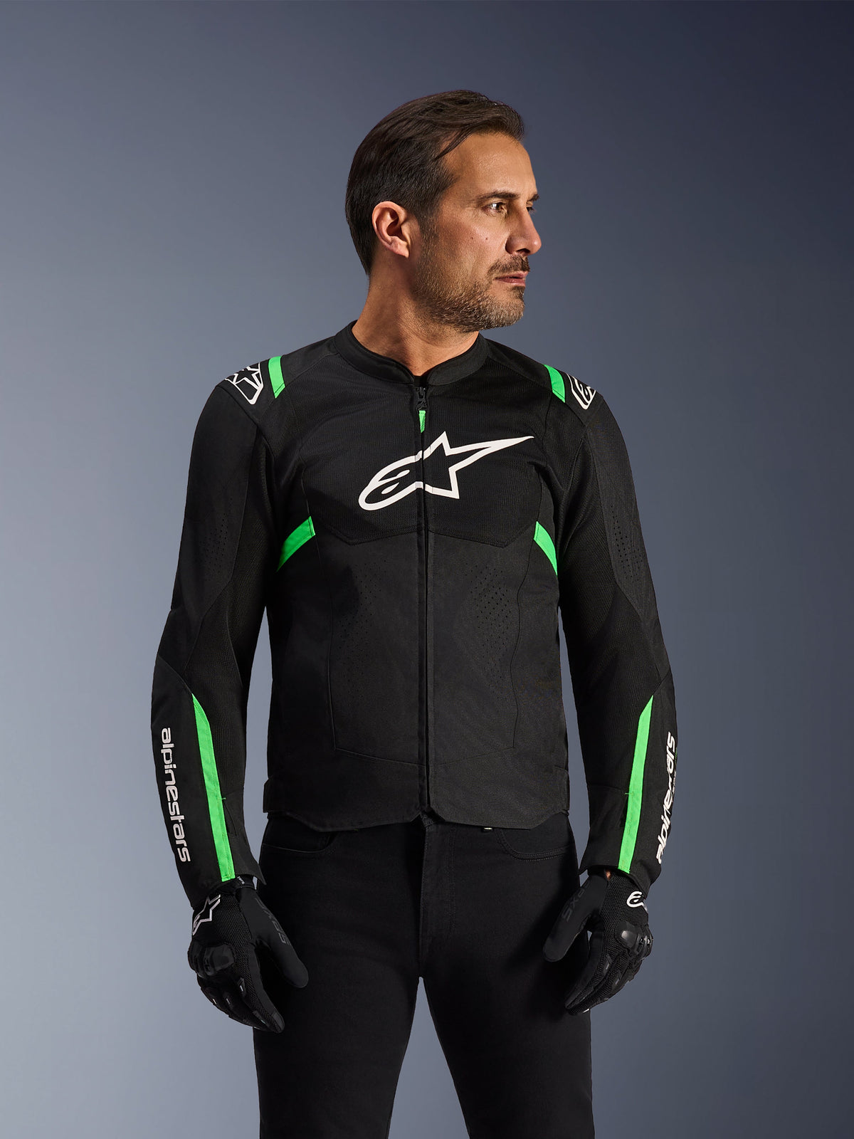 Casaco Alpinestars T-SPS Air V2, casaco de motociclismo, preto e verde fluo, vestido por um modelo com luvas e calças de condução pretas, com logótipo Alpinestars branco no peito e detalhes em verde néon nos ombros e mangas, painéis em malha técnica para ventilação, design de corte desportivo para condução urbana