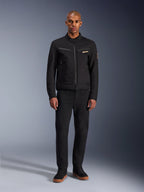 Casaco Alpinestars Bruiser, casaco de motociclismo urbano preto, usado por modelo com calças pretas e sapatilhas de cano alto, vista frontal com bolsos de peito com fecho e logótipo bordado, design clássico inspirado em vestuário de trabalho para deslocações quotidianas