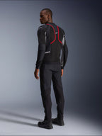 Alpinestars Troop-Air Pro Jacket, casaco de motociclismo, preto, cinzento e vermelho vivo, vista de costas num modelo, com linhas de realce vermelhas e painéis de ventilação em malha, usado com calças e botas pretas, estilo de motociclismo urbano