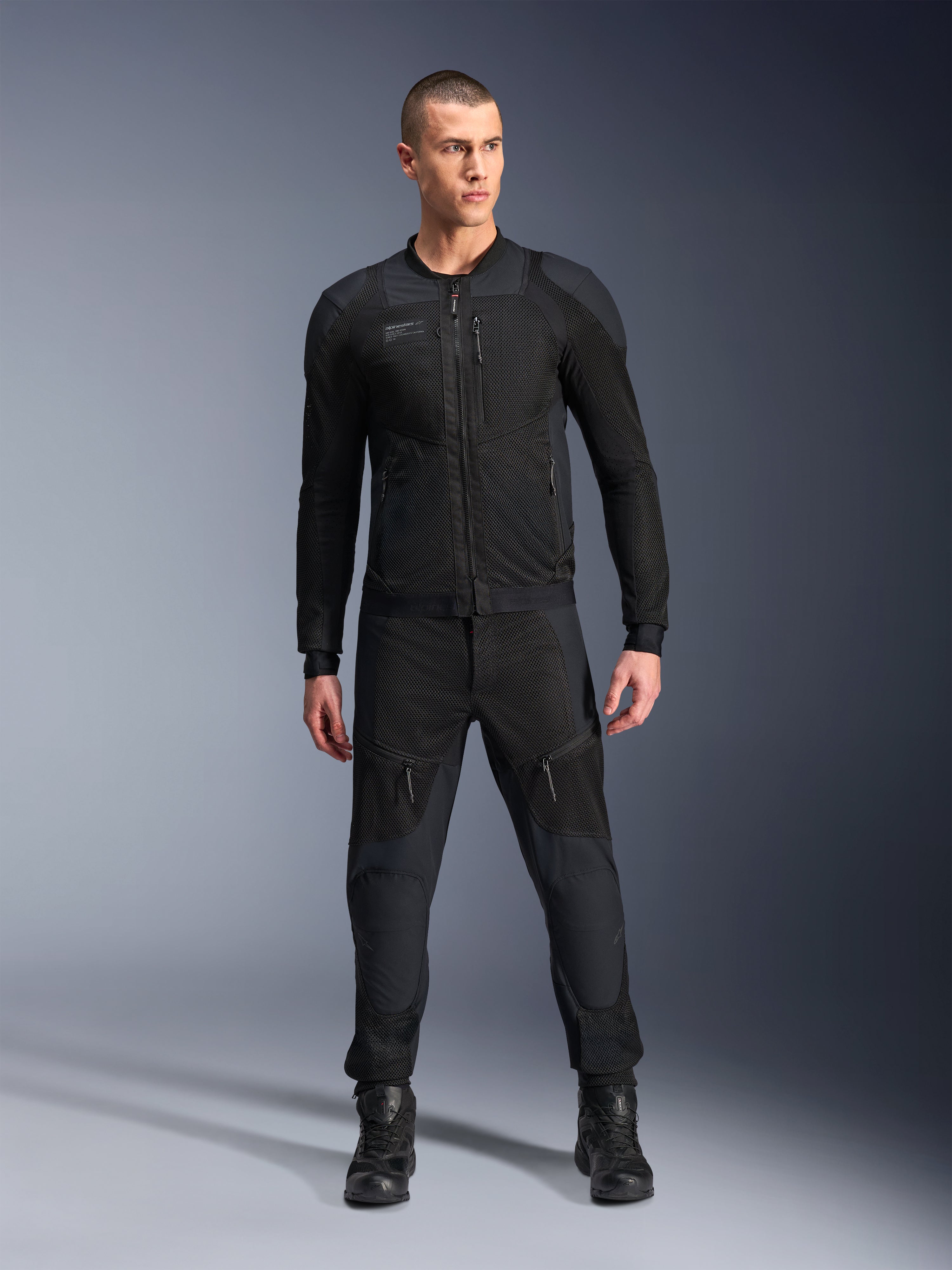Alpinestars Troop-Air Pro Jacket, casaco de motociclismo técnico blindado preto, com painéis de malha e fechos frontais, usado com calças pretas a condizer e botas de condução, equipamento urbano premium