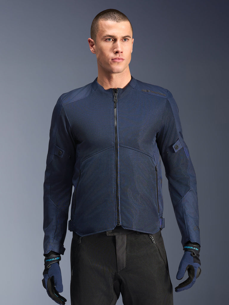 Alpinestars C-1 Air Jacket, casaco de motociclismo azul, usado por um modelo masculino com calças pretas e luvas azuis e pretas a condizer, com painéis de malha técnica para fluxo de ar, design urbano simples com fecho frontal e logótipos subtis