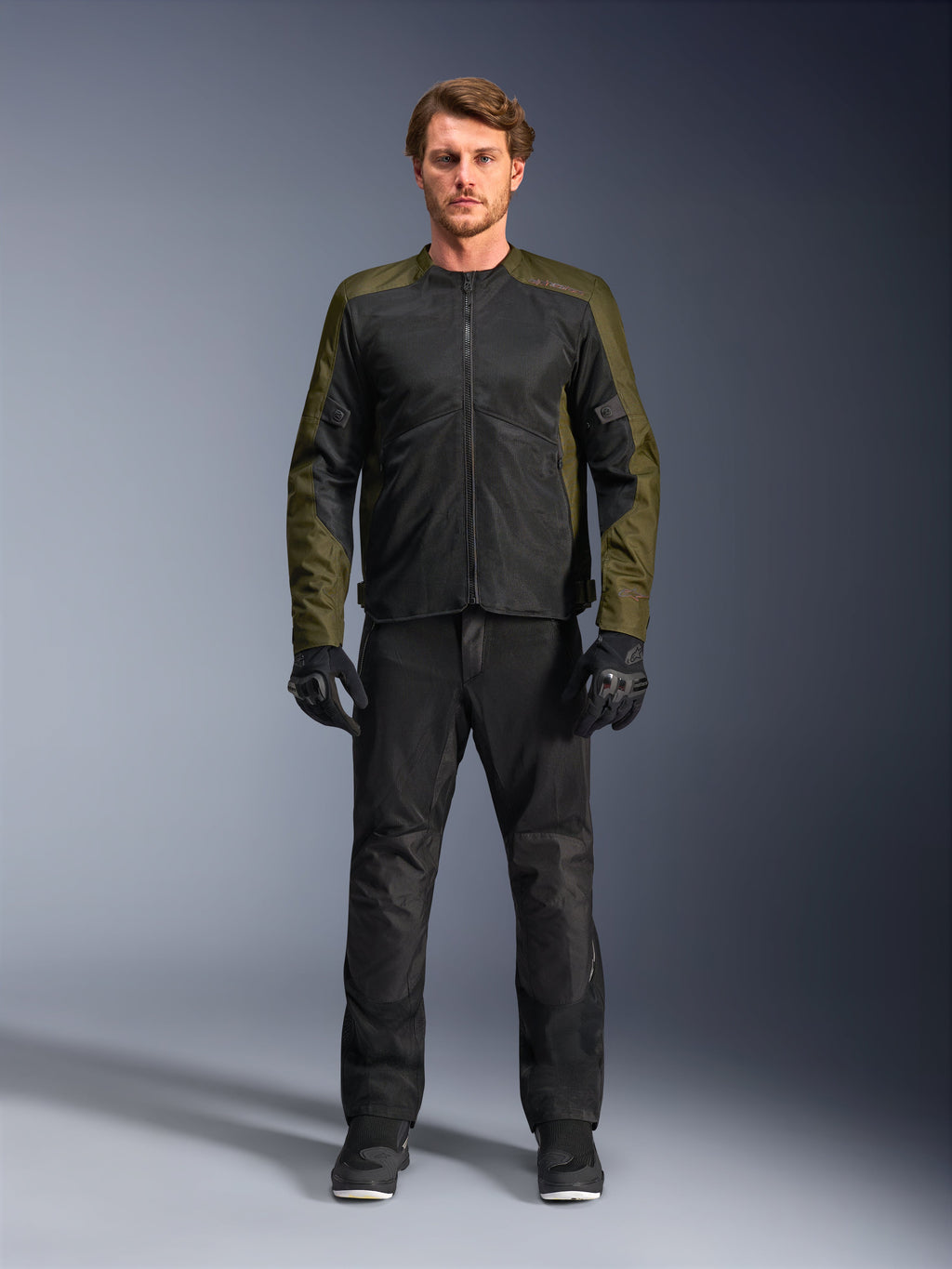 Casaco Alpinestars C-1 Air, caqui e preto, vestido por modelo masculino com calças e luvas de motociclismo pretas, design têxtil leve com painéis de malha técnica, equipamento de condução urbano contemporâneo