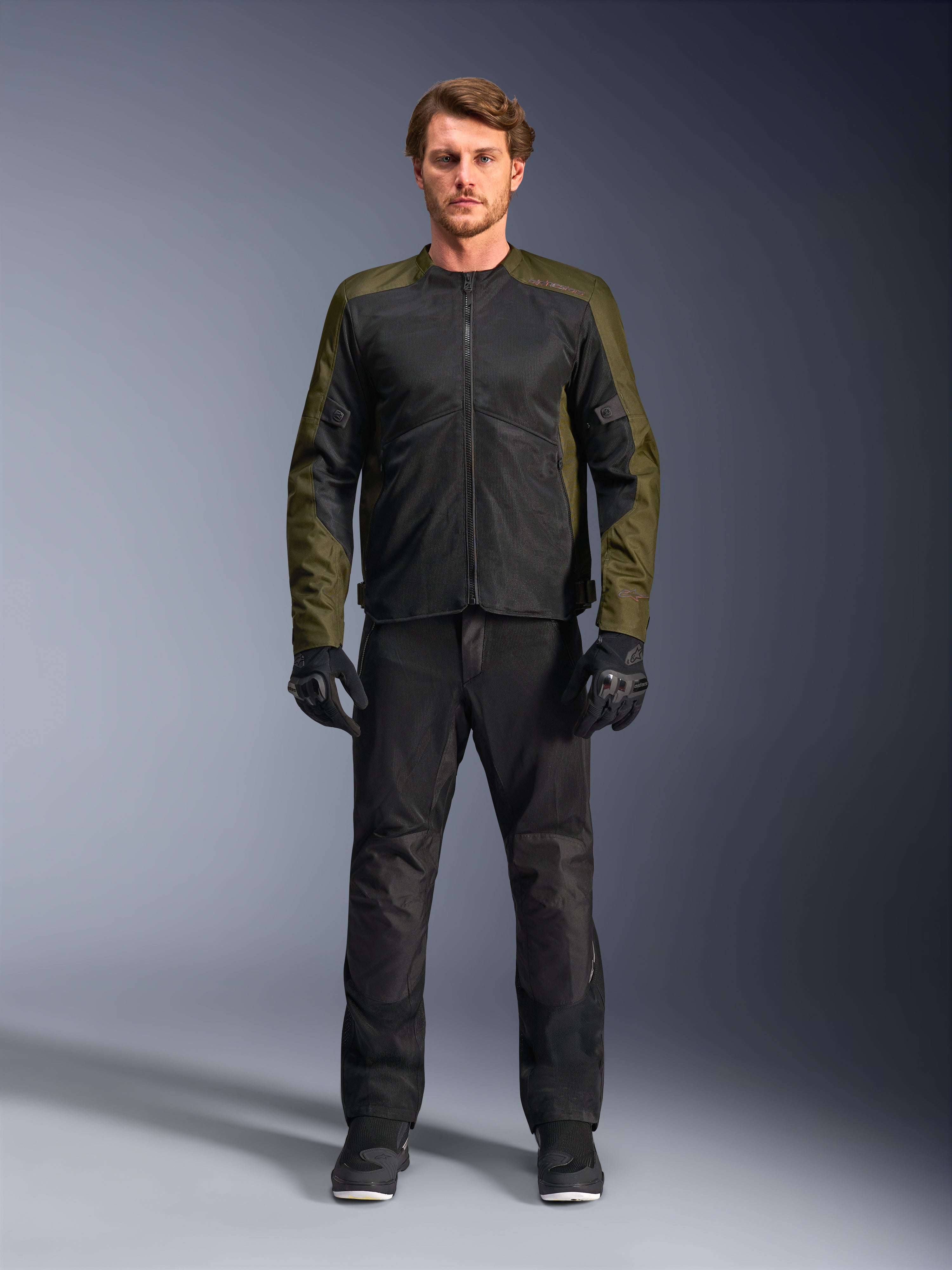 Casaco Alpinestars C-1 Air, caqui e preto, vestido por modelo masculino com calças e luvas de motociclismo pretas, design têxtil leve com painéis de malha técnica, equipamento de condução urbano contemporâneo