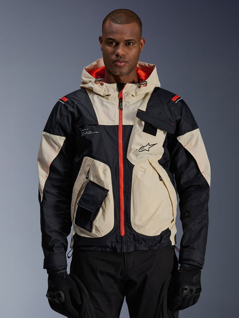 Casaco Alpinestars Mogress Air, casaco de motociclismo urbano, amêndoa e preto com fechos e forro do capuz em laranja vibrante, design com capuz e bolsos utilitários, logótipo no peito, usado com luvas pretas