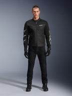 Male model wearing Alpinestars T-Dyno Air Jacket, Black, lightweight textile motorcycle jacket with breathable 3D mesh, white star logos on sleeves, paired with black pants, gloves, and boots, front view standing