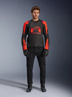 Casaco Alpinestars T-Stunt Air, preto, vermelho fluo e vermelho escuro, usado por um modelo com calças de ganga e luvas de motociclismo pretas, com um design modular 2 em 1 e painéis de malha para fluxo de ar, equipamento de motociclismo com corte desportivo para estrada