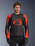 Alpinestars T-Stunt Air Jacket, casaco de motociclismo em tecido, preto, vermelho fluorescente e vermelho escuro, com logótipo de estrela grande e painéis em malha para circulação de ar, usado por modelo com luvas pretas