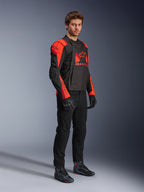 Casaco Alpinestars T-Stunt Air, preto, vermelho fluo e vermelho escuro, casaco de motociclismo modular usado por um modelo com os painéis frontais abertos para revelar o interior em malha, combinado com calças, luvas e sapatos pretos