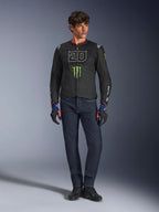 Male rider wearing the Alpinestars FQ20 T-SPS Air V2 Monster Jacket, black with green Monster Energy logo and white '20' graphic on the chest, paired with dark blue jeans and technical riding gloves, urban sport motorcycle outfit.
