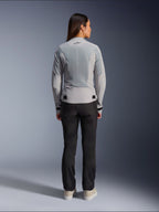 Woman wearing Alpinestars Stella C-1 Air Jacket in Silver, back view, featuring large tech mesh panels for ventilation and a reflective star logo, paired with black riding pants and white sneakers, urban contemporary motorcycle gear