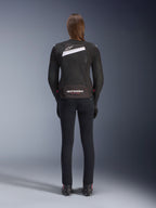 Alpinestars Stella T-GP Plus R V4 Airflow Jacket, Black and White, rear view showing extensive mesh ventilation panels and Alpinestars branding, worn by a female rider with slim-fit black motorcycle pants and boots, sport-fit textile gear for women
