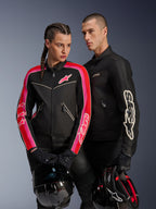 Alpinestars Stella T-Dyno Air Jacket on woman in Black Bright Red Fuchsia, paired with men's black Dyno Air Jacket, both riders holding motorcycle helmets, studio shot of urban contemporary motorcycle gear