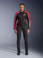 Female rider wearing the Alpinestars Stella T-Dyno Air Jacket, Black with Bright Red and Fuchsia accents, paired with black motorcycle pants and lace-up boots, featuring 3D mesh panels, tailored fit, and pink star logos, urban riding gear outfit