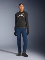 Female rider wearing the Alpinestars Stella SMX Air Jacket, Black with White and Red Fluo branding, paired with blue denim riding pants and black gloves, sporty ventilated textile jacket for road riding