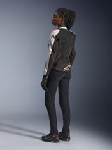 Woman rider wearing the Alpinestars Stella SMX Air Jacket in Ice Gray Black and Coral Fluo, back view. Paired with black motorcycle pants, gloves, and riding shoes, featuring mesh construction and the Alpinestars logo on the lower back.